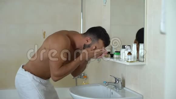 男人在镜子前的浴室洗脸被干燥的面部皮肤干扰视频的预览图