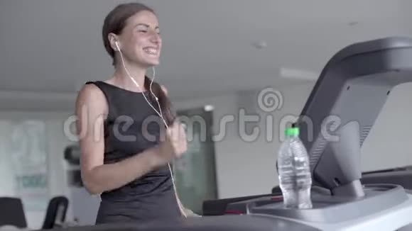 在健身中心运动员们在跑步机上跑步听音乐视频的预览图