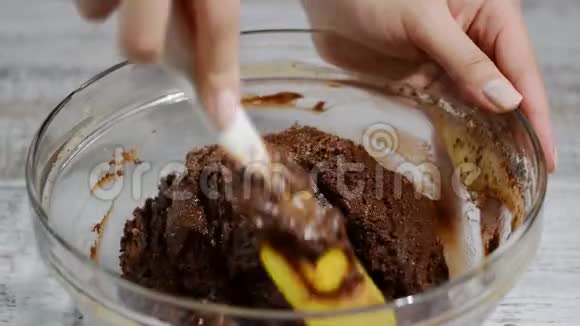 女孩用铲子搅拌巧克力面团制作巧克力面糊的过程视频的预览图
