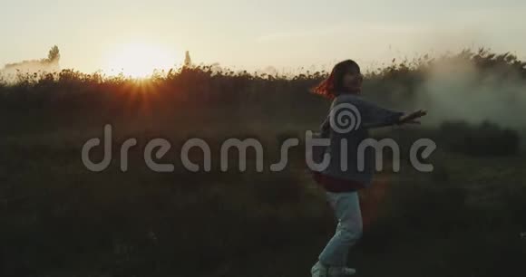 一个年轻的女孩在长长的绿草中旋转视频的预览图