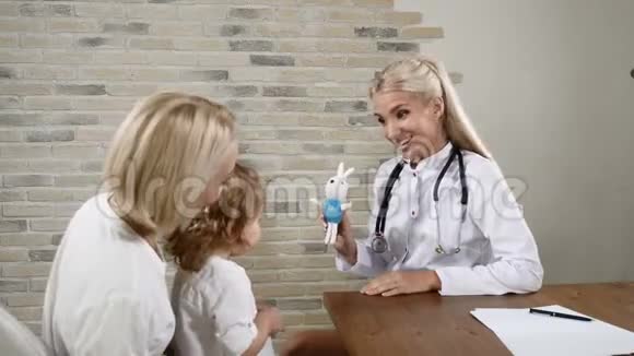 友好的儿科医生被年轻的母亲和她漂亮的小女儿迷住了家庭诊所的概念4k视频的预览图
