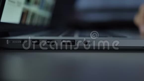 近距离直接拍摄的手与笔记本电脑工作并插入白色USB电缆在黑桌背景视频的预览图