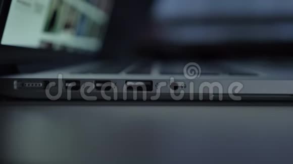 近距离直接拍摄的手快速插入白色USB电缆到笔记本电脑在黑桌背景视频的预览图