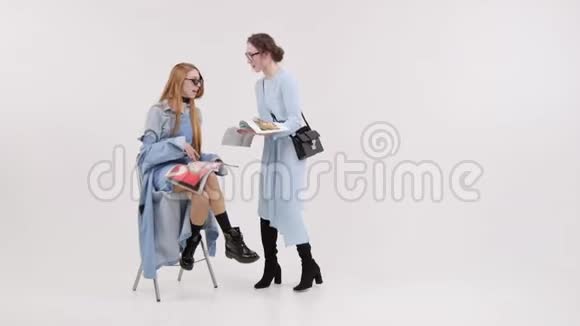 两个女人在白色工作室看风格杂志微笑视频的预览图