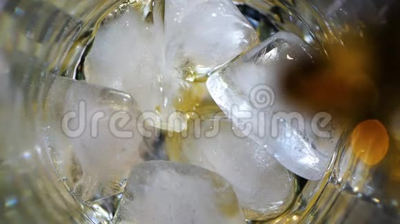威士忌倒入一杯冰在黑暗的背景下上景视频的预览图
