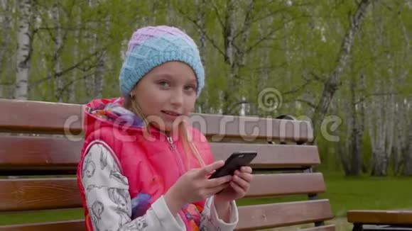 年轻快乐的女孩在公园里慢动作地用电话视频的预览图