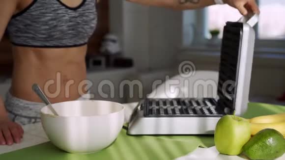 早上一位运动的女士在厨房里做美味的比利时蓝莓华夫饼作为早餐视频的预览图