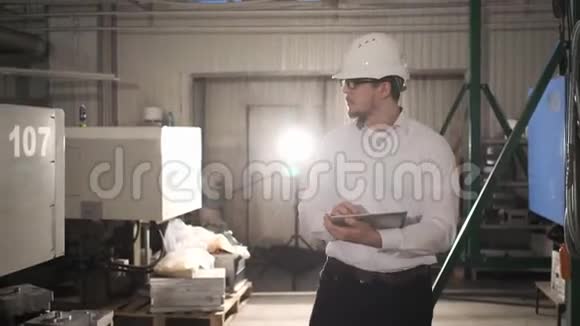 戴着安全帽的工程师正带着平板电脑穿过一家重工业工厂慢动作视频的预览图