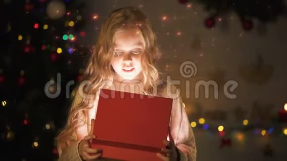 可爱的金发女孩打开礼盒神奇的圣诞气氛发光的效果视频的预览图