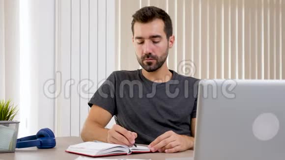 穿着便服的男人在笔记本上写字视频的预览图
