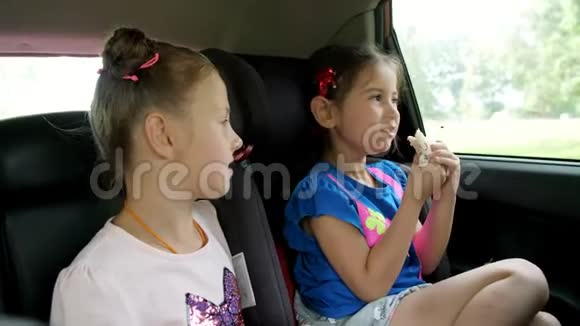 两个小女孩坐在汽车后座上其中一个坐在汽车座位上另一个年长的女孩坐在附近视频的预览图