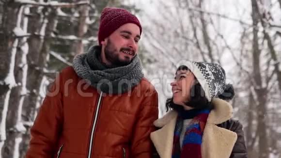 一对相爱的年轻夫妇在下雪的时候在公园里散步男人和女友手牵手在冬日赏雪视频的预览图