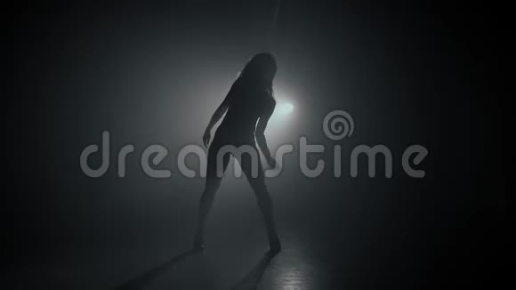 在烟雾弥漫的黑暗背景上美丽的舞者的剪影聚光灯照在后面视频的预览图