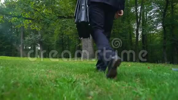 男人把公文包放在草地上走在绿色的森林里逃避压力视频的预览图