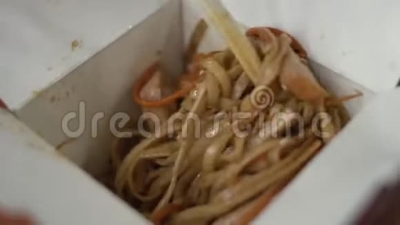 女孩把乌登和鸡肉和木制筷子混合在一个外卖盒里视频的预览图