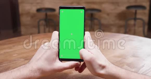 静态镜头男性手拿手机与绿色屏幕显示视频的预览图