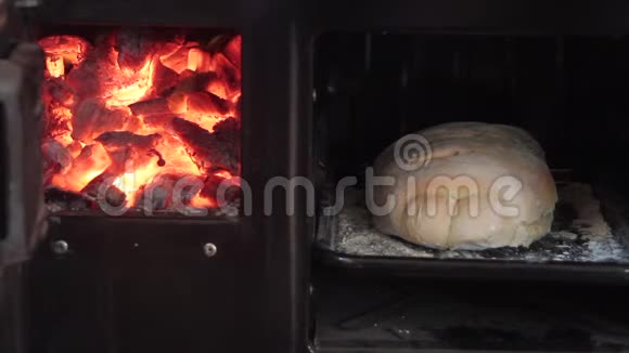 刚出炉的面包从燃烧木头的烤箱里烤出来旁边放着火余烬闪闪发光视频的预览图