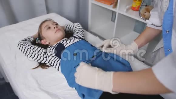 女医生在一个医疗办公室里触诊了一个小女孩病人的腹部特写视频的预览图