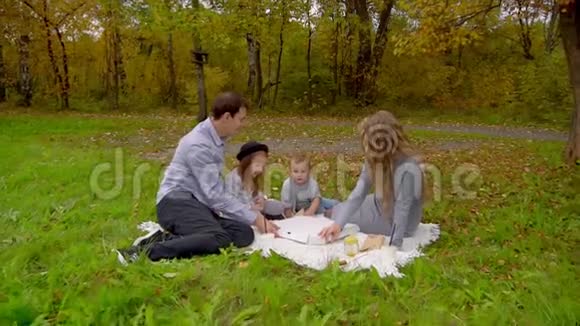 秋天公园的家人在草坪上吃披萨视频的预览图