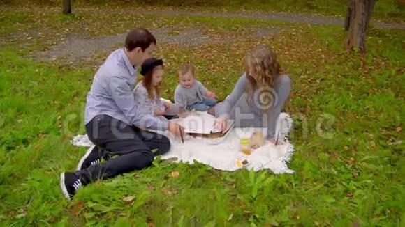 秋天公园的家人在草坪上吃披萨视频的预览图