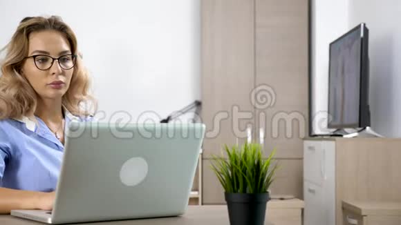 疲惫而稳重的女人在电脑上工作而她的男朋友在后台戴着虚拟现实耳机视频的预览图