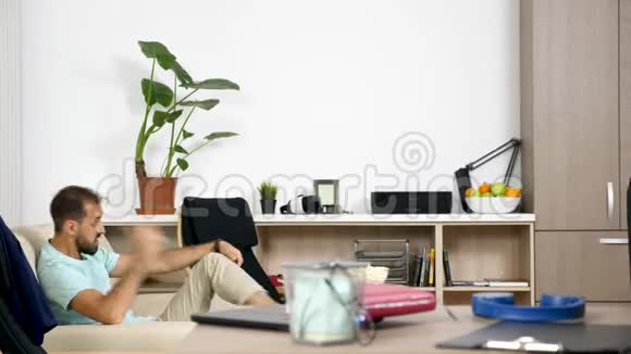 男人在看足球比赛时大声喧哗而她的伴侣则在电脑上工作视频的预览图