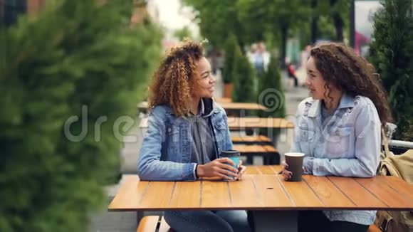 漂亮的年轻女性在户外咖啡馆休息时先品尝咖啡然后喝咖啡聊天视频的预览图