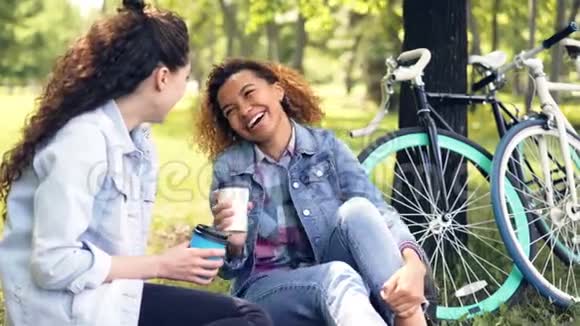 年轻的非洲裔美国妇女正在和她的白人朋友聊天喝着外卖咖啡在美丽的地方放松视频的预览图