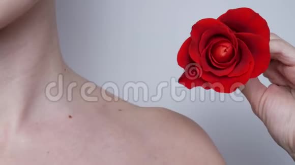 红玫瑰在一个年轻的白人女孩的手中靠近肩部和颈部视频的预览图