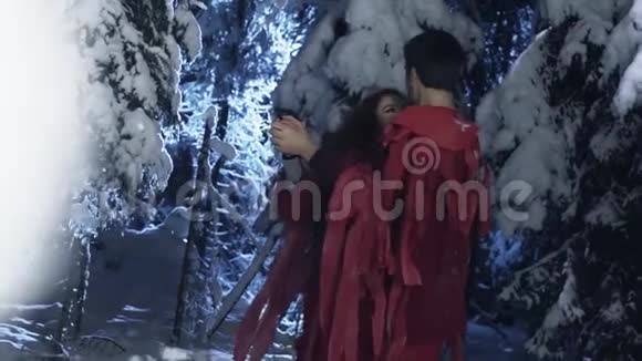 穿着红色服装的年轻可爱的男女在白雪皑皑的冬林中跳舞视频的预览图