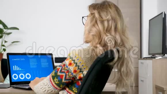 女人看着客厅电脑上的动画财务图表视频的预览图
