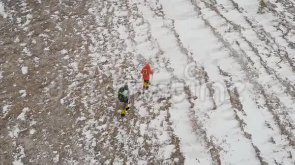 鸟瞰两个雄性徒步旅行者在未触及的雪山景观中行走旅游旅行的人的风景视频的预览图