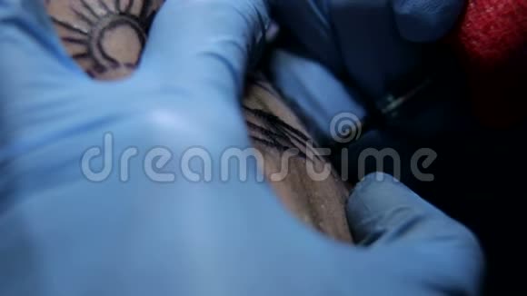一个纹身艺术家的特写在沙龙里一个男人的手臂上做纹身视频的预览图