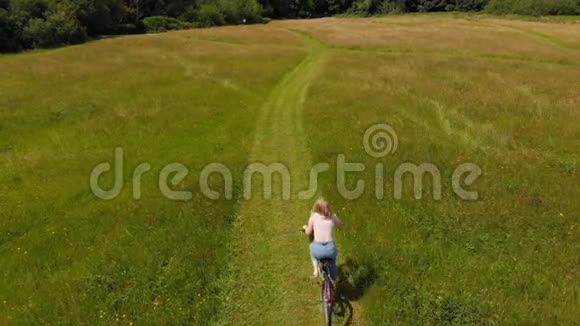 骑自行车的女人骑着绿色的田野视频的预览图