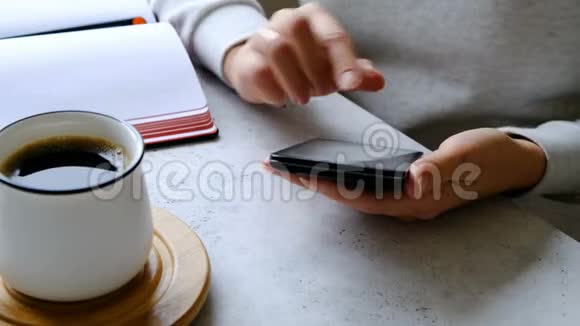 智能手机在妇女手中咖啡和笔记本在桌子上关门视频的预览图