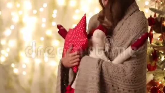 带着格子的年轻女人和圣诞老人手里拿着一个星星形状的枕头走在圣诞树旁边视频的预览图