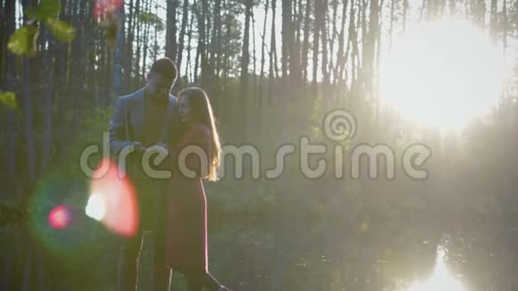 一对浪漫的情侣站在湖边亲吻他们之间有阳光和阳光视频的预览图