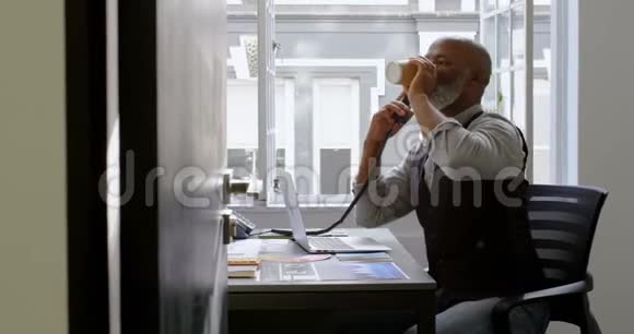 商务人员在座机上一边喝咖啡一边在桌子4k上使用笔记本电脑视频的预览图