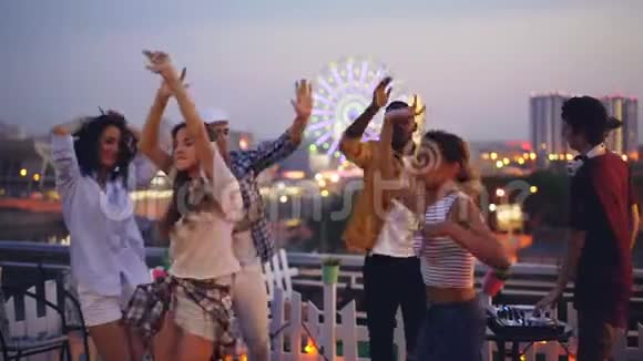 慢动作的晚屋顶派对与快乐的人跳舞享受自己和男性迪杰混合现代音乐视频的预览图
