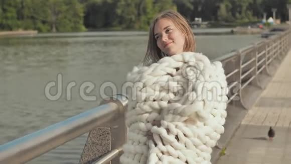 这个女孩正在绕着城市的湖走在初秋裹着一层白色的美利奴羊毛格子视频的预览图