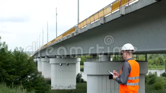 一位建筑师检查了河上桥梁的状况并记录了数据和桥梁视频的预览图