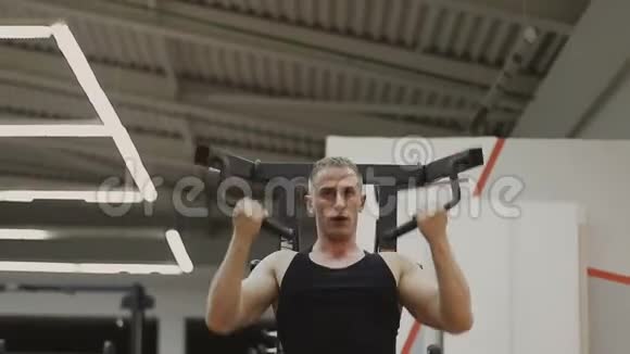 一个穿着黑色T恤的肌肉男正在健身俱乐部的健身机上训练视频的预览图