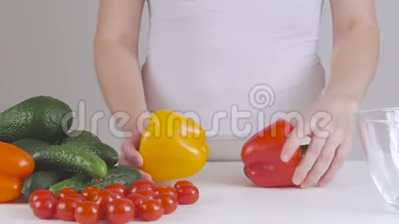 女人选择蔬菜做沙拉在桌子附近涂上两个大辣椒视频的预览图