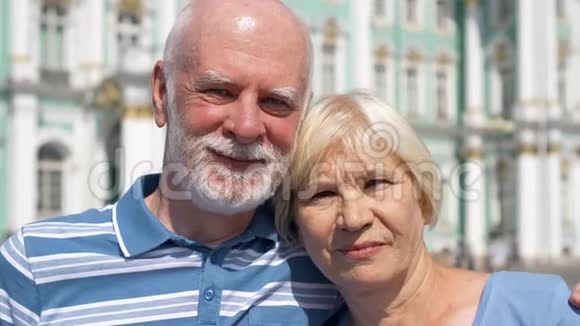 老两口站在皇宫广场上看镜头养老金领取者在俄罗斯圣彼得堡旅行视频的预览图