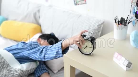 年轻的亚洲男孩睡觉关掉闹钟从床上掉下来视频的预览图