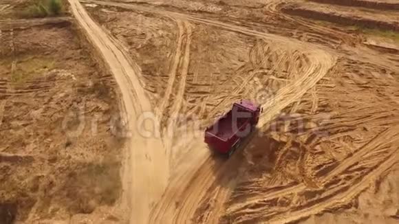 空的大型红色卡车在沙漠或沙丘中的沙子轨道上移动的鸟瞰图美丽的景色视频的预览图