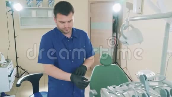 慢慢地给年轻的医生拍照他的肖像一个人在他的牙科办公室准备接待病人穿上视频的预览图