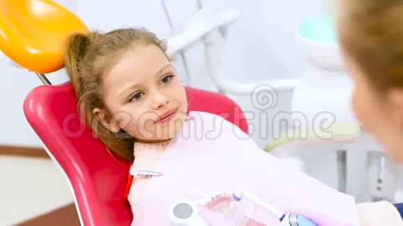 牙医教这个孩子一个没有前乳牙的小可爱女孩如何在牙椅上清洁牙齿视频的预览图