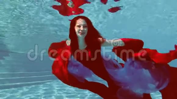 一个穿着红色连衣裙红头发的漂亮女孩在室外游泳池游泳手里拿着一块红色和蓝色的布视频的预览图