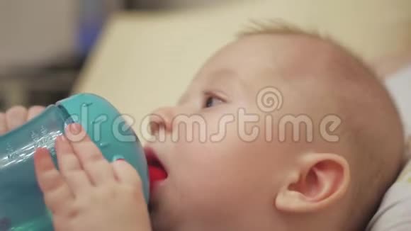 可爱的小男孩在家里用瓶子吸水视频的预览图